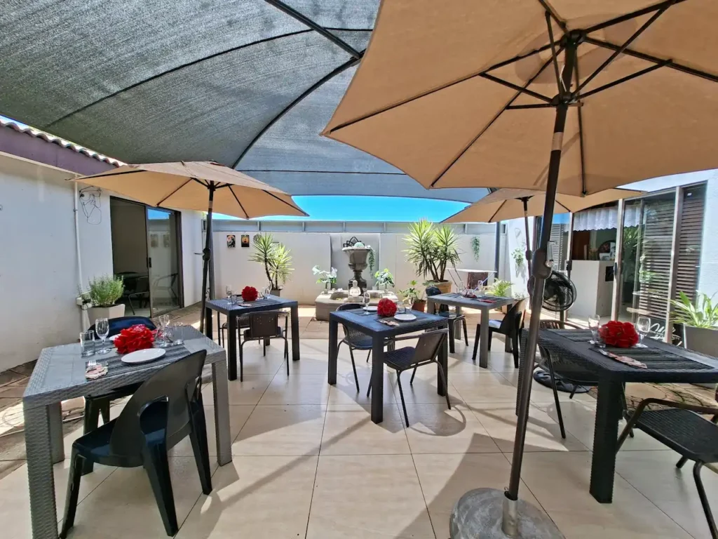 Outdoor dining patio at The Zen Den in Risiville, Meyerton, with shaded tables, umbrellas and romantic red rose centrepieces.