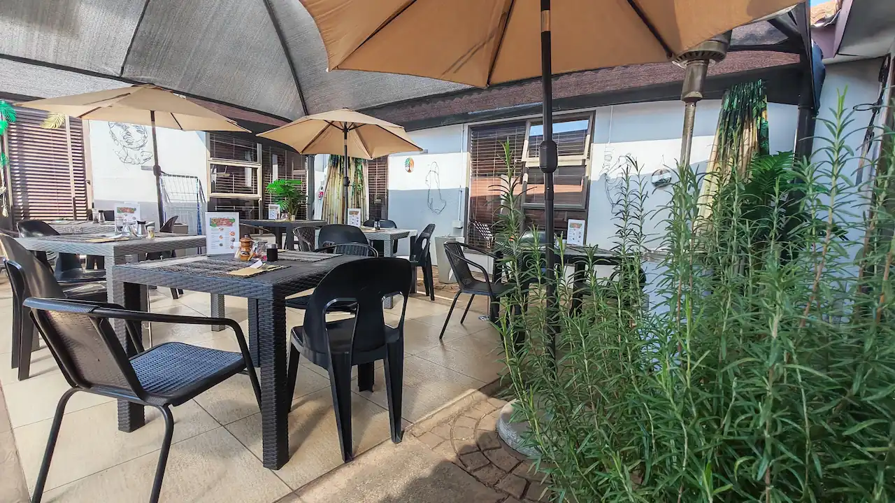 Outdoor patio seating at The Zen Den in Risiville, Meyerton, with dining tables, umbrellas and surrounding greenery.